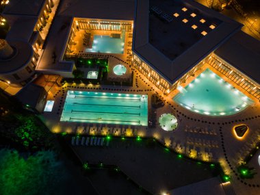 Aerial top view of several pools in the spa center on a sea coast at night