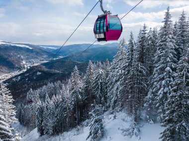 Modern ski lift gondola against snowcovered fir forest and mountains, no people