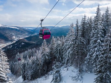 Modern ski lift gondola against snowcovered fir forest and mountains, no people