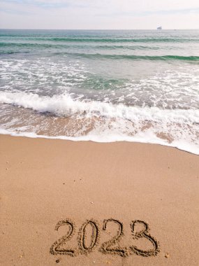 2023 year written on sandy beach ocean at sunny day