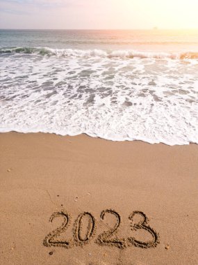 2023 year written on sandy beach ocean at sunny day
