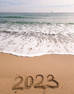 2023 year written on sandy beach ocean at sunny day