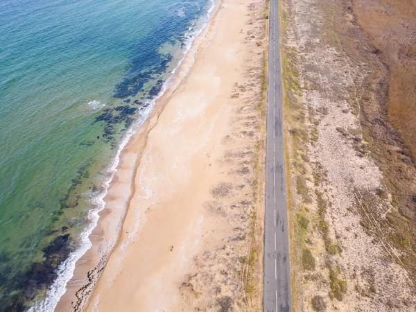 Aerial View of the road along the sea sandy coast. cars drive on the road along the sea
