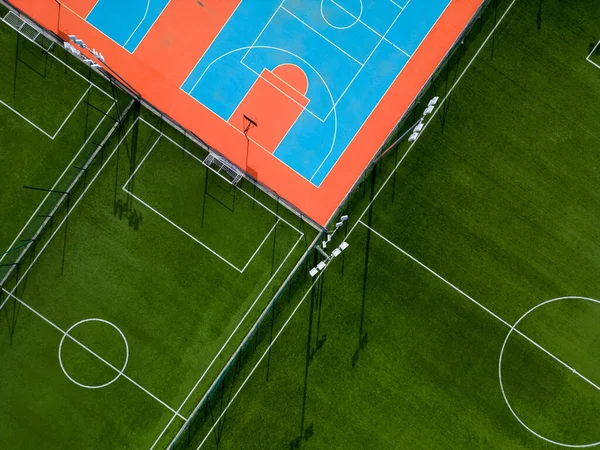 鸟瞰一个绿色的足球场和一个五彩缤纷的篮球场 可以看到两个不同的体育设施并存 绿色和充满活力的色彩形成了鲜明的反差 — 图库照片