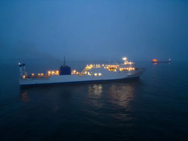 stock image Aerial view of a ferryboat navigating through foggy conditions at night on the sea. The combination of the dark setting, the foggy conditions, and the presence of the ferryboat can create an eerie and