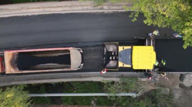 Asfalt kaldırımlar, silindirler, makineler ve işçiler olarak yeni bir yol inşa etmenin havadan görüntüsü hayati bir ulaşım bağlantısı oluşturmak için bir araya geliyor. Etkileyici koordinasyon ve takım çalışmasına tanık olun.