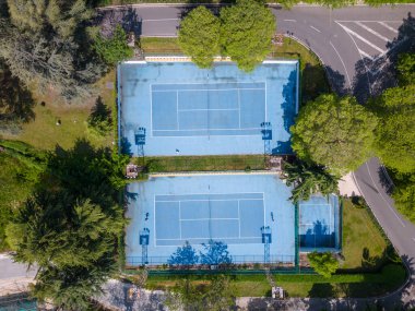 Yukarıdan bakıldığında, mavi kortta tenis oynayan iki kişinin yukarıdan görünüşü