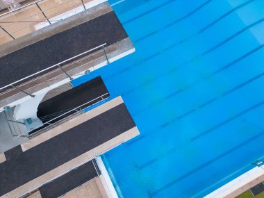 Dalgıç kuleleri, havuzun kristal mavi sularıyla zıtlaşan canlı varlıkları ile dik dururlar. Havadan üst görünüm