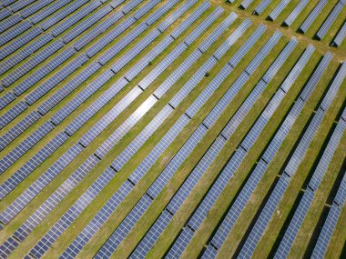 Bereketli bir çayır ve ormanın ortasında güneş panelleri, güneşin enerjisinden yararlanmak için uzun süre ayakta kalır. Işıl ışıl yüzeyleri, canlı gökyüzünü yansıtarak büyüleyici bir görüntü yaratıyor. İnsansız hava araçlarından yakalanmış.