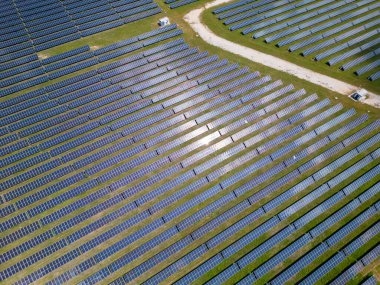 Bereketli bir çayır ve ormanın ortasında güneş panelleri, güneşin enerjisinden yararlanmak için uzun süre ayakta kalır. Işıl ışıl yüzeyleri, canlı gökyüzünü yansıtarak büyüleyici bir görüntü yaratıyor. İnsansız hava araçlarından yakalanmış.