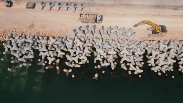挖掘机勤勉地在海里建造码头或防波堤 其有力的臂膀从岸上伸出 在波浪中形成弹性结构 空中俯瞰 — 图库视频影像