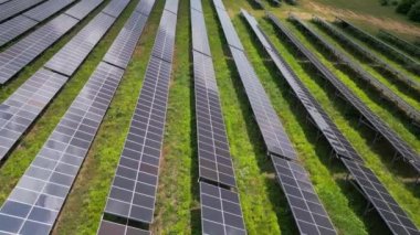 Bereketli bir çayır ve ormanın ortasında güneş panelleri, güneşin enerjisinden yararlanmak için uzun süre ayakta kalır. Işıl ışıl yüzeyleri, canlı gökyüzünü yansıtarak büyüleyici bir görüntü yaratıyor. İnsansız hava araçlarından yakalanmış.