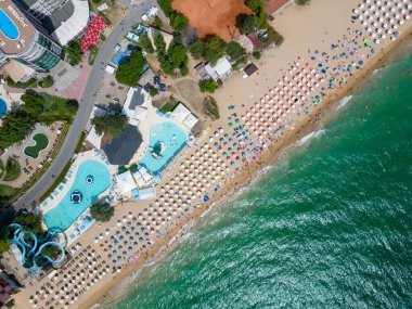 Bulgar Altın Kumlar tatil beldesinin yaz mevsiminde havadan görünen manzarası: bir dizi otel, havuz ve denizin keyfini çıkaran insan.