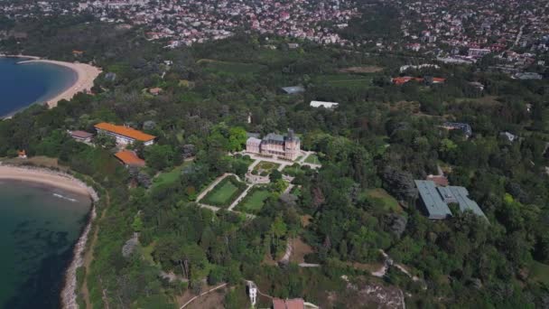 ブルガリアのヴァルナの歴史的なエクシノグラード宮殿の空想的な眺め 美しい黒海沿岸に位置するこの壮大な土地の壮大な建築と緑豊かな庭園を鑑賞してください ドローンフライト — ストック動画