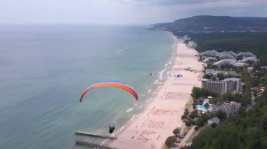 Bulgaristan 'ın Albena tatil beldesinin nefes kesici manzarasıyla deniz ve orman üzerinde süzülen bir paraglider unutulmaz bir deneyim yaratıyor. İHA uçuş videosu.