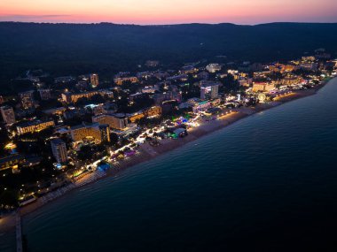 Bulgar tatil beldelerinin kıyı şeridinin büyüleyici insansız hava aracı görüntüsü. Parıldayan ışıklar ve huzur dolu gece büyüsü.