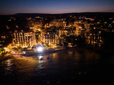 Geceleri, bir İHA Bulgaristan kıyısındaki lüks bir sahil tatil beldesinin açılışını yapıyor. Işıklar sıcaklığın ve lüksün büyülü atmosferini yaratır..