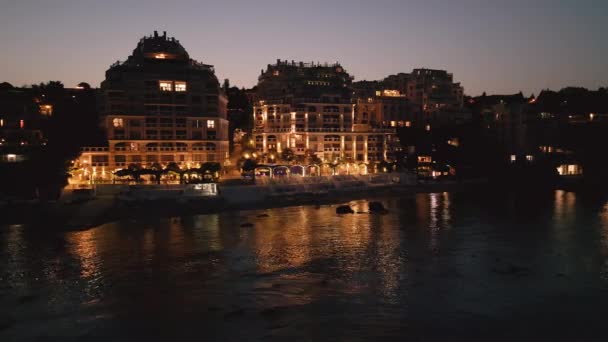夜には ドローンがブルガリア沿岸の豪華なシーサイドリゾートホテルを発表します ライトは暖かさと贅沢の魔法の雰囲気を作ります — ストック動画