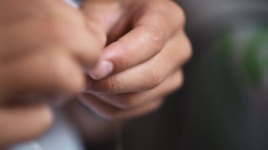 Bir çocuk özenle narin boncuk işçiliği yapıyor, özümsenmiş odaklı karmaşık süsler dokuyor. Eller tutkulu bir şekilde küçük şaheserler yaratmak için çalışıyor. Yakın çekim