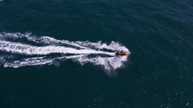 Dalgaların arasından hızla geçen kişisel bir su aracının havadan görünüşü büyüleyici bir iz yaratıyor..