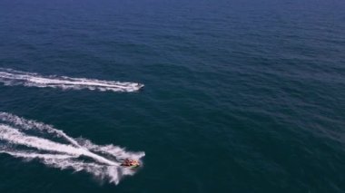 Dalgaların arasından hızla geçen kişisel bir su aracının havadan görünüşü büyüleyici bir iz yaratıyor..