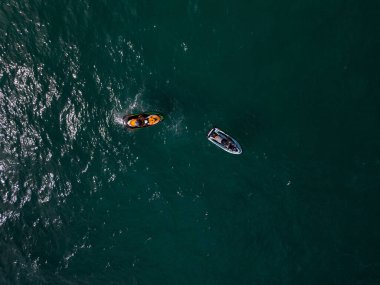 Dalgaların arasından hızla geçen kişisel bir su aracının havadan görünüşü büyüleyici bir iz yaratıyor..