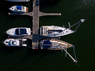 Deniz kenarında bir yat marinasının havadan görünüşü, zarif yatlarla süslenmiş, pitoresk bir deniz manzarası yaratıyor..