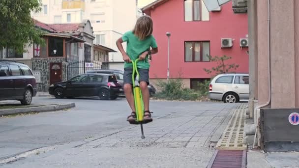Ein Jähriger Junge Führt Freudig Tricks Auf Einem Pogo Stick — Stockvideo