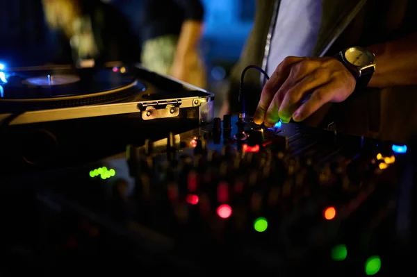 A closeup of the DJs hand on the mixer console in a nightclub, crafting music and dance ambiance.