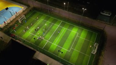 Çocukların futbol ve basketbol oynadığı, futbol ve basketbol sahaları olan bir akşam spor sahasının havadan görünüşü..