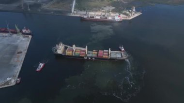 Limandan ayrılırken iki römorkör tarafından desteklenen bir konteynır gemisinin havadan üst görüntüsü