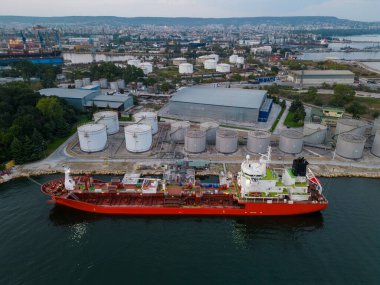 Petrol terminalinde yakıt ikmali yapan bir tanker gemisi limanda depolama siloları var.