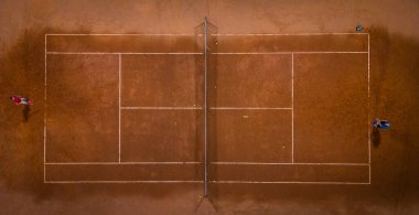 Tenis kortunda iki kişi tenis oynuyor, yukarıdan aşağıya doğru.