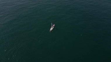 Durgun bir denizde kürek çeken bir adamın ya da SUP tahtasının havada görüntüsü..