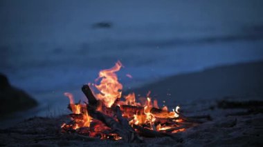 Akşamları deniz kıyısındaki ıssız bir kumsalda bir kamp ateşi yanıyor..