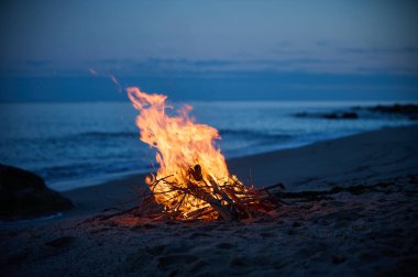 Akşamları deniz kıyısındaki ıssız bir kumsalda bir kamp ateşi yanıyor..