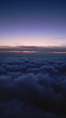 Gün batımında kabarık bulutların üzerinde bir dron uçar. İnsansız hava aracı bulutların arasında uçuyor, merak ve korku hissi yaratıyor..