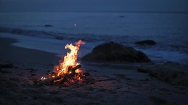 Akşamları deniz kıyısındaki ıssız bir kumsalda bir kamp ateşi yanıyor..