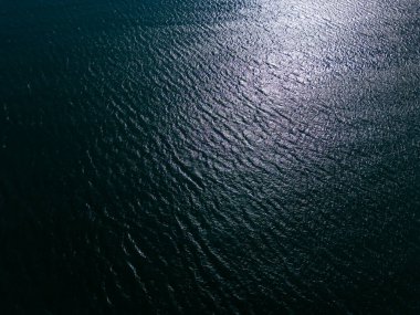 Kanat çırpan dalgalarla dolu görkemli bir mavi denizin hava manzarası, sudan yansıyan güneşin parlak parıltısı..