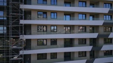 İHA uçuşu, inşaat halindeki modern bir apartmanın ön cephesinde. Etrafı iskelelerle çevrili..