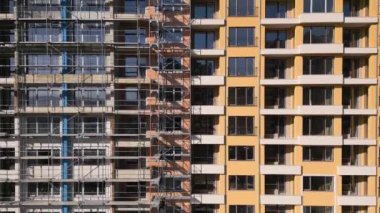İHA uçuşu, inşaat halindeki modern bir apartmanın ön cephesinde. Etrafı iskelelerle çevrili..