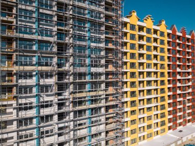 İHA uçuşu, inşaat halindeki modern bir apartmanın ön cephesinde. Etrafı iskelelerle çevrili..