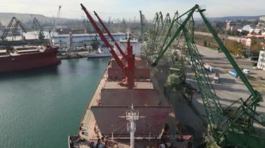 Aerial view of big cargo ship bulk carrier is loaded with grain of wheat in port at sunset.