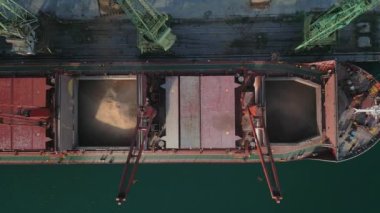 Aerial view of big cargo ship bulk carrier is loaded with grain of wheat in port at sunset.