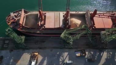 Aerial view of big cargo ship bulk carrier is loaded with grain of wheat in port at sunset.