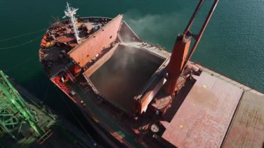 Aerial view of big cargo ship bulk carrier is loaded with grain of wheat in port at sunset.