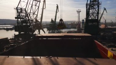 Aerial view of big cargo ship bulk carrier is loaded with grain of wheat in port at sunset.