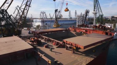 Aerial view of big cargo ship bulk carrier is loaded with grain of wheat in port at sunset.