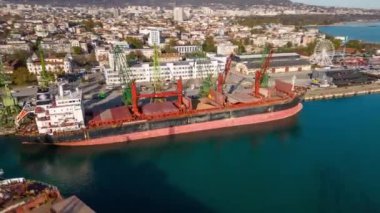 Aerial view of big cargo ship bulk carrier is loaded with grain of wheat in port at sunset.