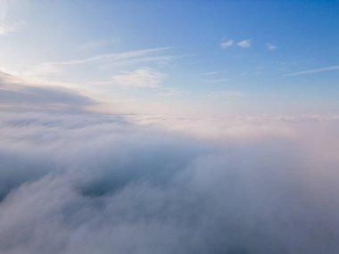 Bir dron kabarık bulutların üzerinde uçar. İnsansız hava aracı bulutların arasında uçuyor, merak ve korku hissi yaratıyor..